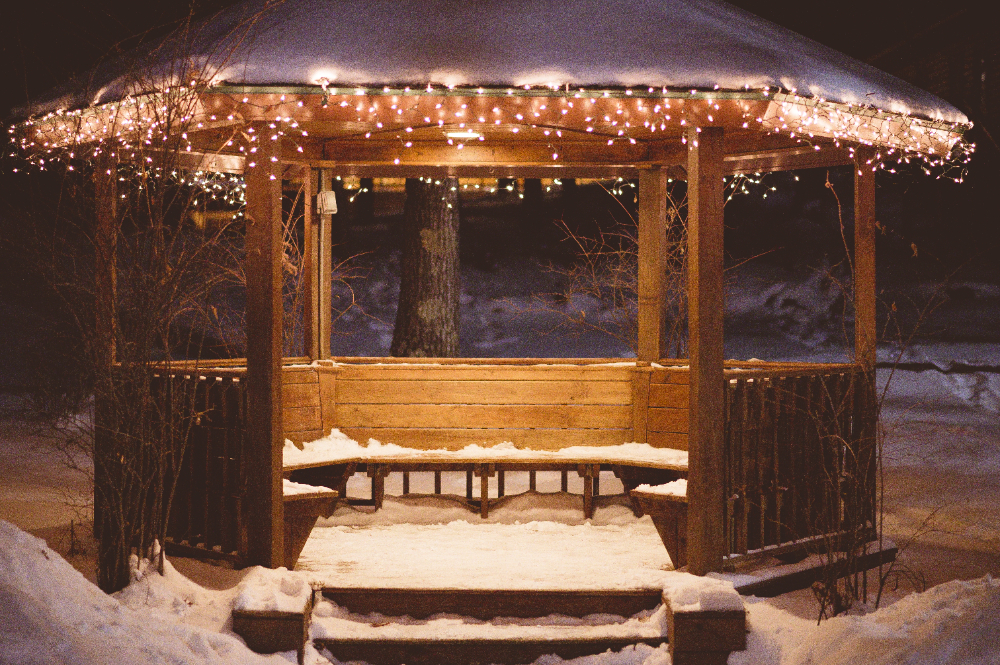 A snowy gazebo with glowing string lights at night in a park in Indio, CA, creating a peaceful winter scene.