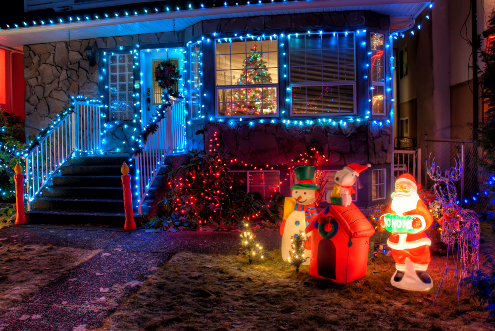 A brightly lit house in Indio, CA, featuring colorful Christmas lights, snowman, and Santa figurines set up in front of the yard.