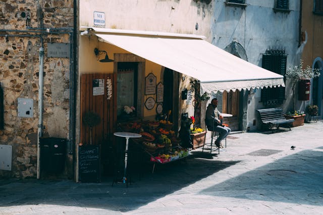 Retractable awning over a charming café in a European street setting, offering shade for outdoor dining and aesthetic appeal.