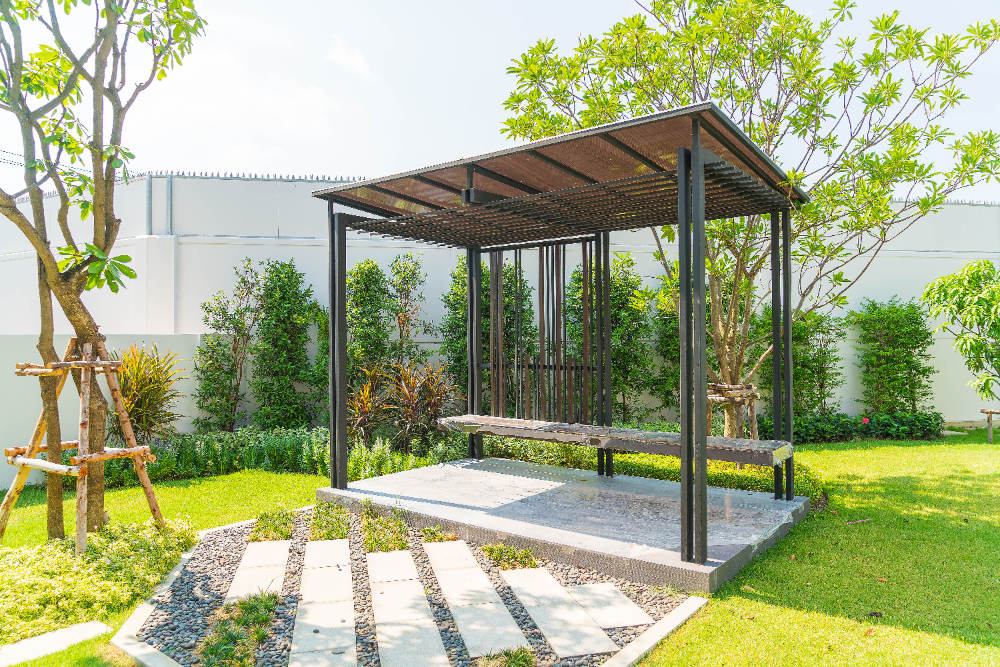 Modern pergola with black metal frame in a lush green backyard garden