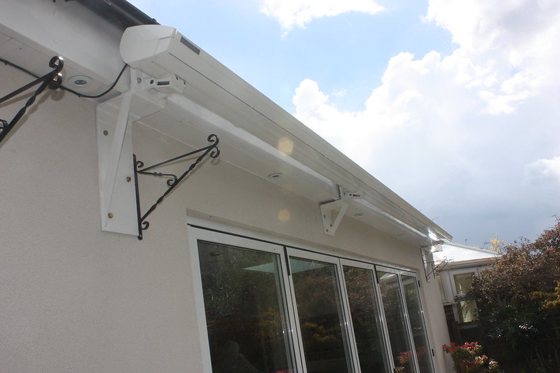 A white house in Indio, California, featuring a white roof and windows, complemented by a stylish retractable awning on the porch.