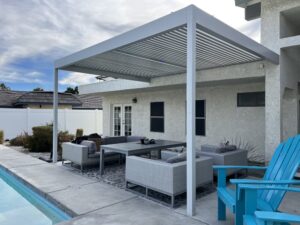 1 Outdoor patio in Indio, California, showcasing a blue chair beneath a white pergola, perfect for enjoying the sun.